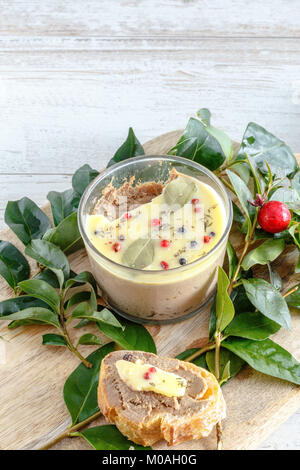 Huhn Leber pate Jar mit zerlassener Butter bedeckt und mit Lorbeerblättern und schwarze und rote Paprika eingerichtet. Stockfoto