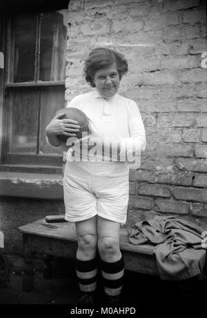 Schwarz-weiß-Foto aus dem frühen 20. Jahrhundert zeigt eine Frau in einem Fußball (Fußball) Kit gekleidet, und halten und Old style Fußball aus Leder. Stockfoto