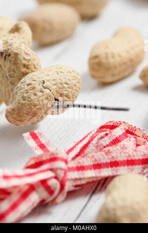 Erstellen einer schnellen, Winter herzförmigen Bird Feeder von Monkey nuts (Schritt-für-Schritt Anleitung). Schritt 1/3: Gewinde monkey Muttern auf Craft Wire altmodisch wie Herzen Stockfoto