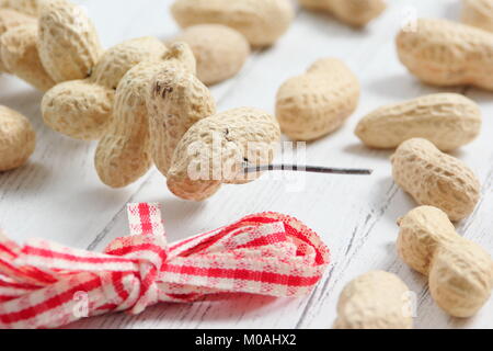 Erstellen einer schnellen, Winter herzförmigen Bird Feeder von Monkey nuts (Schritt-für-Schritt Anleitung). Schritt 1/3: Gewinde monkey Muttern auf Craft Wire altmodisch wie Herzen Stockfoto