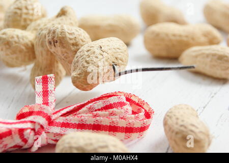 Erstellen einer hausgemachten Winter herzförmigen Bird Feeder von Monkey nuts (Schritt-für-Schritt Anleitung). Schritt 1/3: Gewinde monkey Muttern auf Craft Wire altmodisch wie Herzen Stockfoto