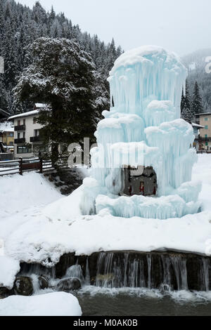 Die gefrorenen Brunnen auf der Piazza von Canazei im Fassatal, mit einem zentralen Weihnachten Szene innerhalb der IT. Bewaldeten Hänge der Dolomiten. Stockfoto