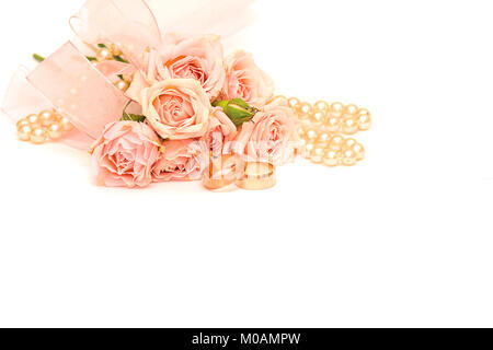 Zwei goldene Ringe, Perlen und zarte Rosen auf weißem Hintergrund Stockfoto