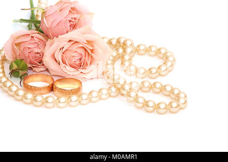 Zwei goldene Ringe, Perlen und Blumen auf weißem Hintergrund Stockfoto