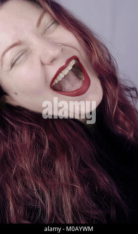 Rote Haare Mädchen mit einem großen Mund lacht, während jemand nimmt das Bild Stockfoto