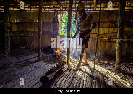 Porträt eines Mannes aus dem Volk der Asmat Menschen mit einer Trommel in der Men's Haus. Asmat Begrüßungszeremonie. Stockfoto