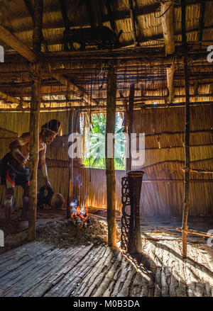 Porträt eines Mannes aus dem Volk der Asmat Menschen mit einer Trommel in der Men's Haus. Asmat Begrüßungszeremonie. Stockfoto