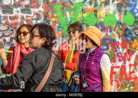 Chinesische Touristen posieren für Fotos vor der mit Graffiti bedeckten John Lennon Wall in Prag, Tschechische Republik Stockfoto