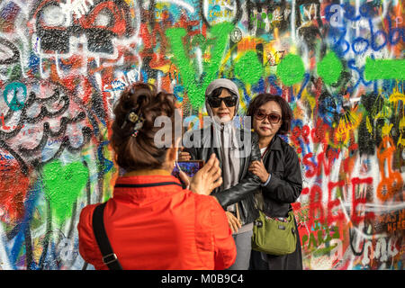 Chinesische Touristen posieren für Fotos vor der mit Graffiti bedeckten John Lennon Wall in Prag, Tschechische Republik Stockfoto