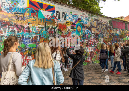 Touristen, die für Fotos posieren und das Graffiti betrachten, das die John-Lennon-Mauer in Prag, Tschechische Republik, bedeckt Stockfoto