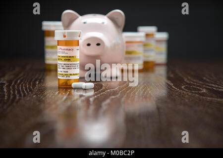 Vielzahl von Non-Proprietary Medizin Flaschen, Pillen und Sparschwein auf reflektierenden Holz- Oberfläche. Stockfoto