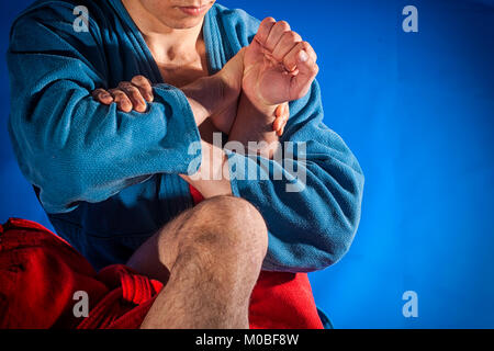 Mann Ringkämpfer der Auseinandersetzung und Jiu jitsu in blauen und roten Kimono macht Submission wrestling. Kampftechniken: armbar armlock, Stockfoto