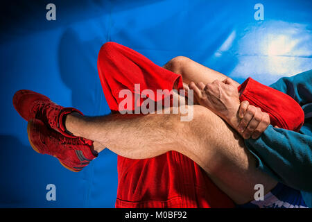 Man Wrestler von sambo und Jiu jitsu in blauen und roten Kimono zu tun, lässt Submission wrestling oder armbar auf blauem Boden. Kampftechniken: armbar, Stockfoto