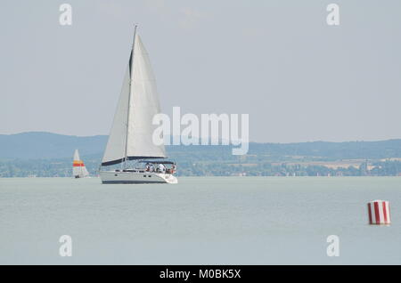 Weißes Segelboot am Plattensee mit rot-weiß gestreiften Boje Stockfoto