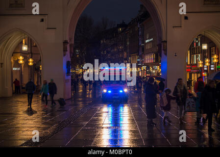 Ein Krankenwagen mit Blaulicht spinnt seinen Weg durch Fußgänger am frühen Abend in der Münchner Fußgängerzone ein Stockfoto