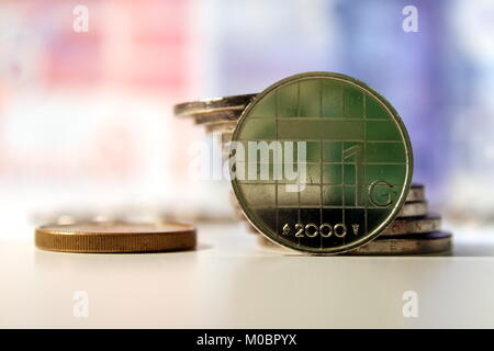 Holländischer Gulden Münze mit niederländischen Banknoten hinter und eine Reflexion eines Grünen 5 Gulden Banknote in der Münze. Alte ehemalige niederländische Währung nicht mehr verwendet. Stockfoto