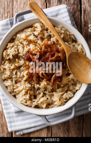 Vegetarische Mujaddara aus Reis und Linsen mit karamellisierten Zwiebeln Makro in eine Schüssel geben. Vertikal oben Ansicht von oben Stockfoto