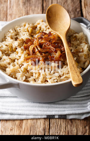 Arabische Küche: Reis mit Linsen und gebratenen Zwiebeln close-up in einer Schüssel auf dem Tisch. Vertikale Stockfoto