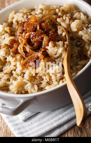 Vegetarische Mujaddara aus Reis und Linsen mit karamellisierten Zwiebeln Makro in eine Schüssel. Vertikale Stockfoto