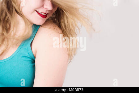 Blonde Frau mit langen Haaren lächelt, während sie ihr Haar fliegt Stockfoto