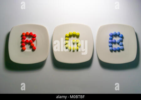 Drei Platten mit bunten Bonbons Pralinen mit RGB-Farben auf weißem Hintergrund Stockfoto