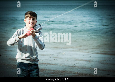 10 Jahre alter Junge flying a Kite durch das Meer bei [Songbook] Bay, Yorkshire, Großbritannien Stockfoto