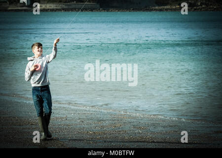 10 Jahre alter Junge flying a Kite durch das Meer bei [Songbook] Bay, Yorkshire, Großbritannien Stockfoto