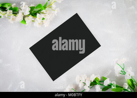 Schiefertafel mit einem leeren Feld mit weißen Blumen auf einem grauen Hintergrund umgeben. Kopieren Sie den Raum. Vorlage für Frühling oder weibliche Urlaub Stockfoto