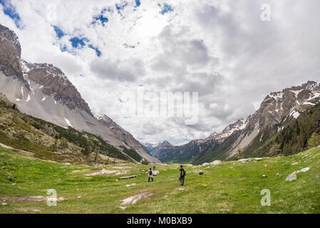 Wanderer Klettern an steilen Bergauf Rocky Mountain Trail. Sommer Abenteuer und Erforschung auf den Alpen. Dramatische Himmel mit Gewitterwolken. Stockfoto