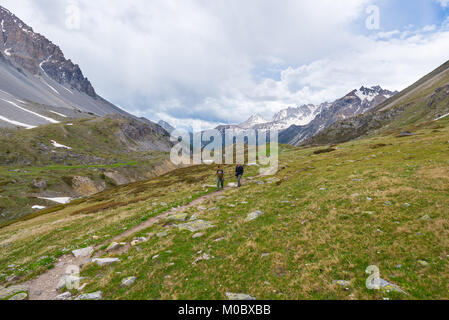 Wanderer Klettern an steilen Bergauf Rocky Mountain Trail. Sommer Abenteuer und Erforschung auf den Alpen. Dramatische Himmel mit Gewitterwolken. Stockfoto