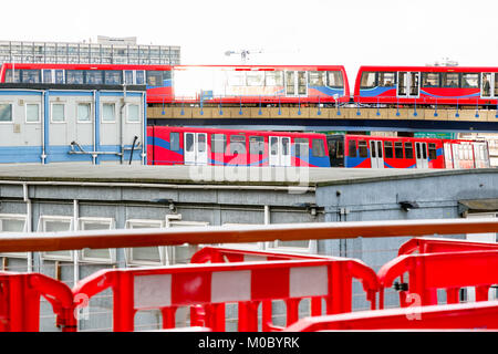 Zwei leichte Züge, die sich kreuzen, durch eine Baustelle in Canary Wharf, London gesehen Stockfoto