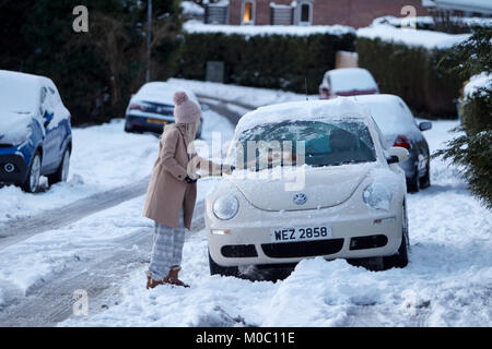 Eine Frau, die Reinigung der Schnee vom Dach Auto im Winter