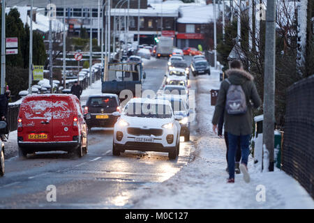 Morgen wird der Verkehr mit Autos und Menschen zu Fuß entlang der Straße im Schnee in Newtownabbey Nordirland Stockfoto