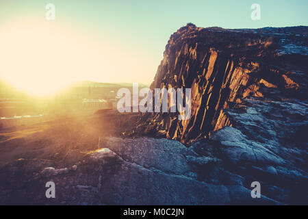 Niedrige Winter Sonne über Edinburgh, Schottland, mit Salisbury Crags im Vordergrund. Stockfoto