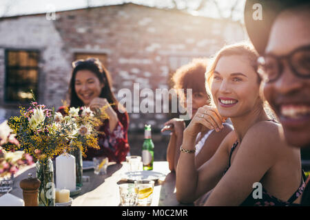 Schöne junge Frau am Tisch sitzen mit Freunden während einer Partei. Multi-ethnischen Gruppe von Menschen, die Mahlzeit im Freien Restaurant. Stockfoto