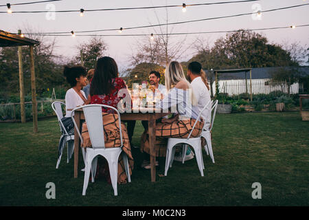 Eine Gruppe von Freunden im Restaurant im Freien sitzen und essen. Junge Männer und Frauen, die im Freien Partei. Stockfoto