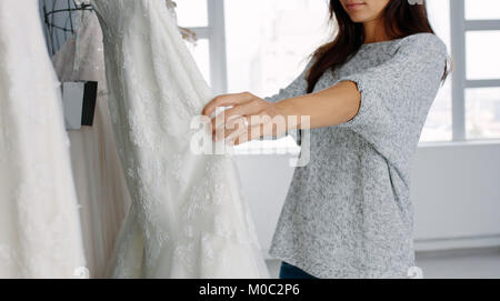 Junge Frau von Brautkleider in Boutique suchen. Fokus auf weibliche Hände Auswahl ein Hochzeitskleid aus Anzeige bei der Hochzeit Fashion Store. Stockfoto