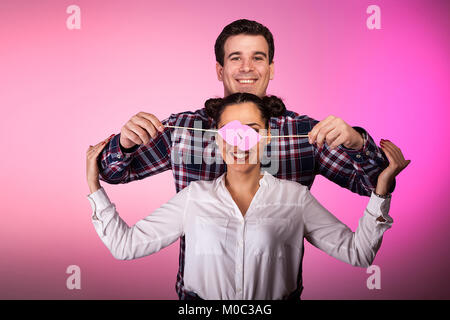 Paar im Studio mit zwei rosa Herzen beeing Dumm Stockfoto