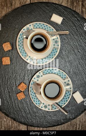 Getränke, Trinkwasser, Energie und Koffein Konzept - zwei Tassen Kaffee auf dunklem Schiefer und Holz- Hintergrund. Stockfoto