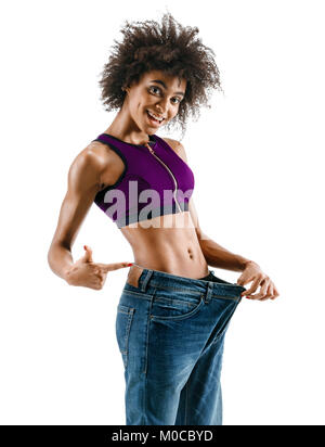 Sportliche Mädchen ihre großen Jeans ziehen und Gewichtsverlust. Foto der afrikanischen Mädchen auf weißem Hintergrund. Kraft und Motivation Stockfoto