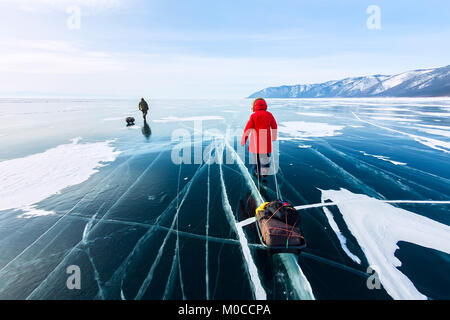 Frau mit einem Schlitten zu Fuß ist auf dem Eis des Baikals. Stockfoto