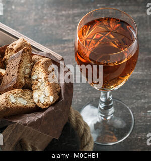 Italienische cantucci Kekse und ein Glas süßen Vin Santo Wein über Holz- Hintergrund Stockfoto