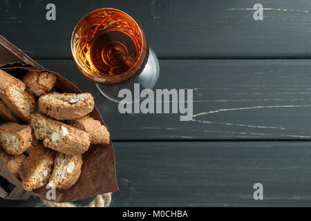 Italienische cantuccini Gebäck und ein Glas süßen Vin Santo Wein über Holz- Hintergrund Stockfoto