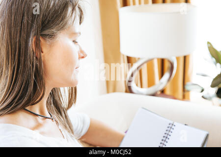 Reife Frau sitzt auf der Couch und wird in Ihrem Notebook Stockfoto
