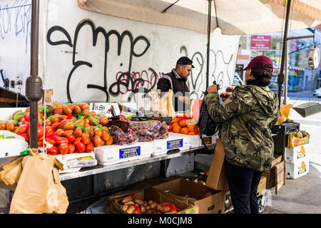 Bronx, USA - Oktober 28, 2017: Günstige Obststand essen Display markt Shop Verkauf Anzeige in Fordham Höhen Center, New York City, NYC, Verkäufer und Frau Stockfoto