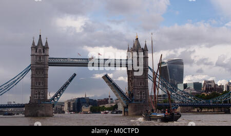 Ein Blick auf einem Segelschiff richtung Westen nähert sich die Tower Bridge, London, mit der Brücke angehoben und der Londoner City im Hintergrund Stockfoto