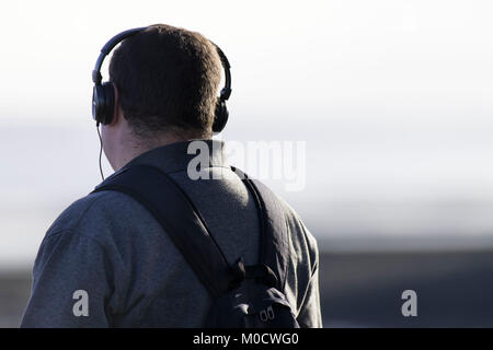 Mann mit drahtgebundenen Kopfhörern weg von der Kamera. Stockfoto