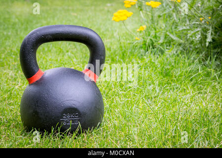 Eisen-Kettlebell auf dem grünen Rasen in einem Hinterhof - outdoor-Fitness-Konzept Stockfoto