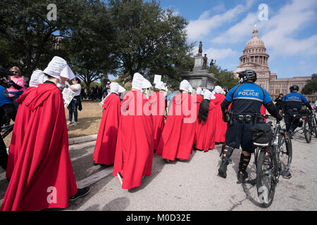 Frauen gekleidet als Zeichen von Buch Margaret Atwood's" ist eine Magd Erzählung "in einer Kundgebung an der Texas Capitol in Austin zum Gedenken an den ersten Jahrestag des März der Frauen auf Washington und politischen Maßnahmen, die sie im ersten Jahr Präsident Donald Trump im Amt erlassen gegen teilnehmen. Stockfoto