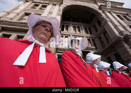 Frauen gekleidet als Zeichen von Buch Margaret Atwood's" ist eine Magd Erzählung "in einer Kundgebung an der Texas Capitol in Austin zum Gedenken an den ersten Jahrestag des März der Frauen auf Washington und politischen Maßnahmen, die sie im ersten Jahr Präsident Donald Trump im Amt erlassen gegen teilnehmen. Stockfoto